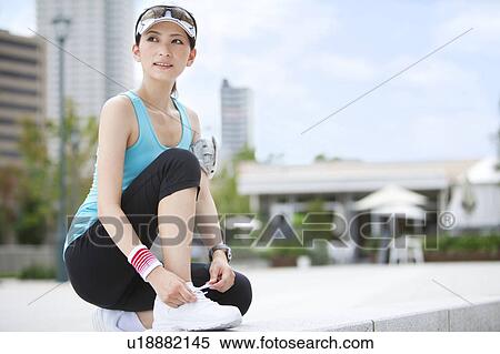 Stock Photography - Sporty Young Woman Tying Shoe Laces. Fotosearch