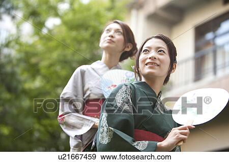 Stock Photo - Two Young Women in Yukata Holding Fan. Fotosearch