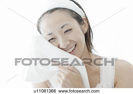 Stock Photo - Woman drying her face with a towel, Tokyo Prefecture, Japan. Fotosearch