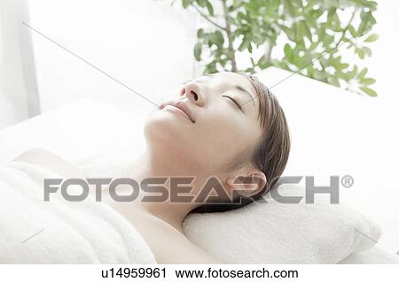 Stock Image - Woman lying on back and eyes closed, Tokyo Prefecture, Japan. Fotosearch