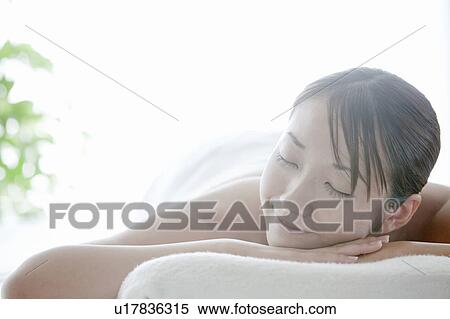 Stock Photography - Woman lying on front and eyes closed, Tokyo Prefecture, Japan. Fotosearch