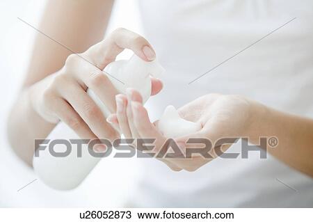 Stock Image - Woman pumping soap dispenser, Tokyo Prefecture, Japan. Fotosearch