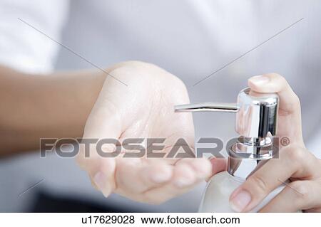 Stock Photo - Woman pumping soap dispenser, Tokyo Prefecture, Japan. Fotosearch