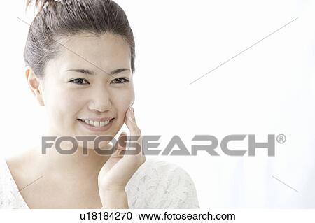 Stock Image - Woman touching her cheek with hand, Tokyo Prefecture, Honshu, Japan. Fotosearch