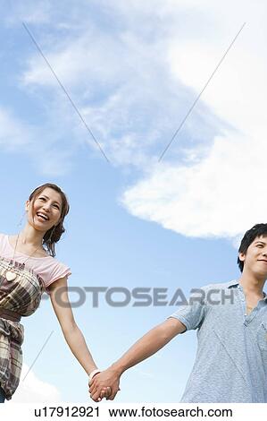 Stock Image - Young Couple Against Blue Sky, Low Angle View. Fotosearch