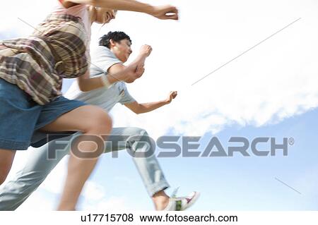 Stock Photo - Young Couple Jumping, Low Angle View. Fotosearch