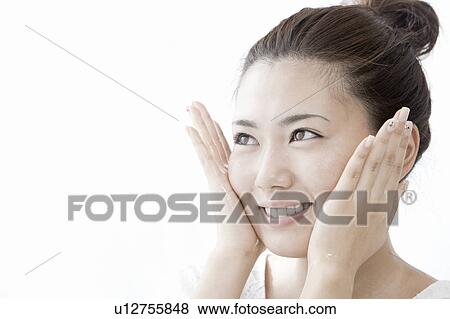 Stock Photo - Young woman applying moisturizer on face, Tokyo Prefecture, Honshu, Japan. Fotosearch