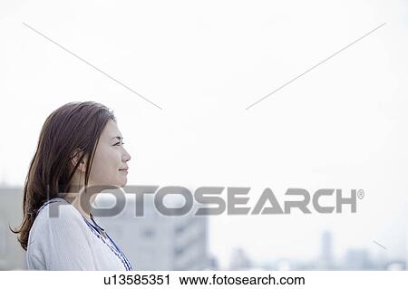 Stock Image - Young woman at balcony looking at cityscape, Tokyo Prefecture, Honshu, Japan. Fotosearch