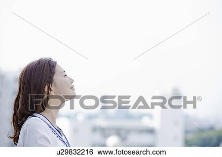 Stock Photograph - Young woman at balcony looking at cityscape, Tokyo Prefecture, Honshu, Japan. Fotosearch