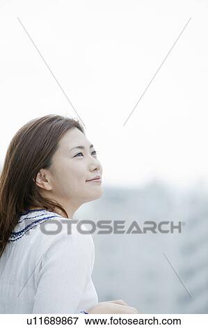 Stock Photo - Young woman at balcony looking up, Tokyo Prefecture, Honshu, Japan. Fotosearch