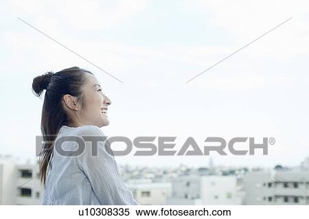 Stock Photography - Young woman at balcony smiling, Tokyo Prefecture, Japan. Fotosearch