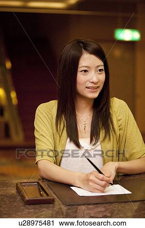 Stock Image - Young Woman Checking In at Hotel. Fotosearch