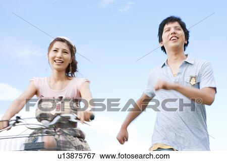 Young Woman Cycling and Boyfriend Running View Large Photo Image Stock Photo - Young Woman Cycling and Boyfriend Running. Fotosearch