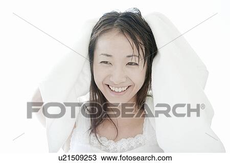 Stock Image - Young woman drying her hair with towel, Tokyo Prefecture, Japan. Fotosearch