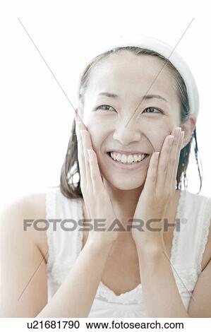 Stock Image - Young woman giving herself a facial massage, Tokyo Prefecture, Japan. Fotosearch