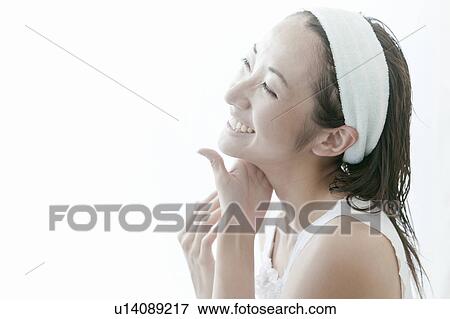 Stock Photo - Young woman giving herself a facial massage, Tokyo Prefecture, Japan. Fotosearch
