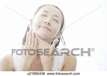 Stock Photo - Young woman giving herself a facial massage, Tokyo Prefecture, Japan. Fotosearch