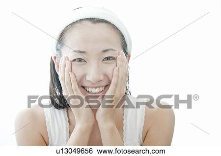 Stock Photograph - Young woman giving herself a facial massage, Tokyo Prefecture, Japan. Fotosearch