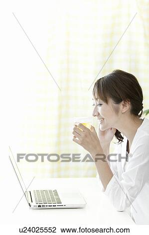 Stock Image - Young woman holding a glass of beer, Tokyo Prefecture, Japan. Fotosearch