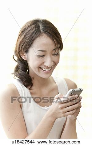 Young woman holding a smart phone, Tokyo Prefecture, Japan View Large Photo Image Picture - Young woman holding a smart phone, Tokyo Prefecture, Japan. Fotosearch