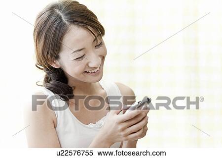 Stock Photography - Young woman holding a smart phone, Tokyo Prefecture, Japan. Fotosearch