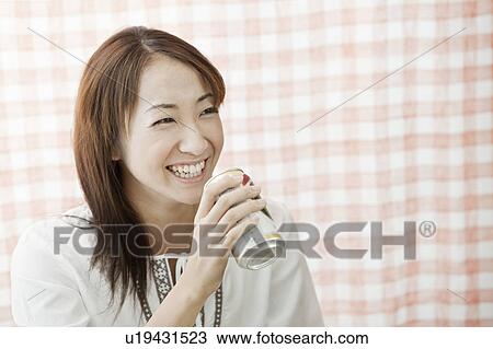 Stock Image - Young woman holding beer can, Tokyo Prefecture, Japan. Fotosearch