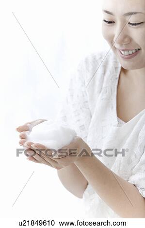 Stock Image - Young woman holding soap suds, Tokyo Prefecture, Honshu, Japan. Fotosearch