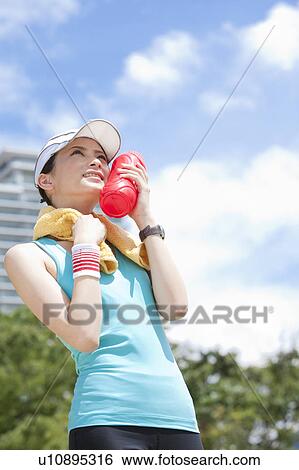 Stock Photograph - Young Woman Holding Water Bottle Against Her Cheek. Fotosearch