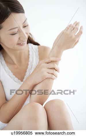Stock Photography - Young Woman Looking At Her Arm. Fotosearch