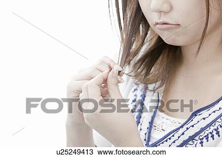 Stock Image - Young woman looking at her hair, Tokyo Prefecture, Honshu, Japan. Fotosearch