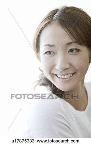 Stock Image - Young woman looking away and smiling, Tokyo Prefecture, Japan. Fotosearch