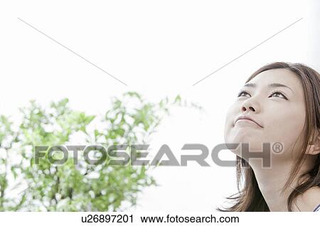 Stock Image - Young woman looking up, Tokyo Prefecture, Honshu, Japan. Fotosearch