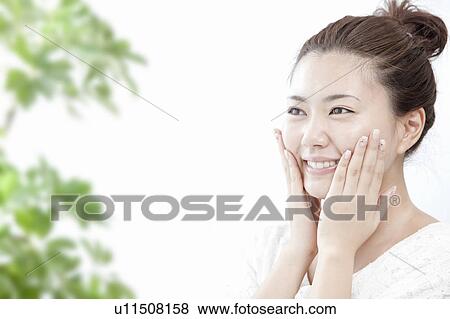 Stock Photo - Young woman massaging her face, Tokyo Prefecture, Honshu, Japan. Fotosearch