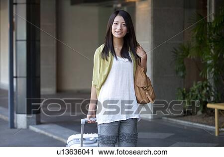 Stock Image - Young Woman Pulling Suitcase. Fotosearch