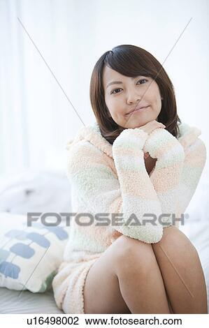 Stock Image - Young Woman Sitting on Bed. Fotosearch