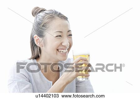 Stock Image - Young woman smiling and holding a glass of beer, Tokyo Prefecture, Japan. Fotosearch
