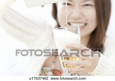 Stock Image - Young woman smiling and pouring beer, Tokyo Prefecture, Honshu, Japan. Fotosearch