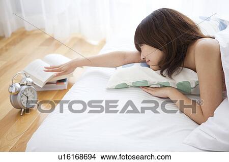 Picture - Young Woman Switching Off Alarm Clock. Fotosearch