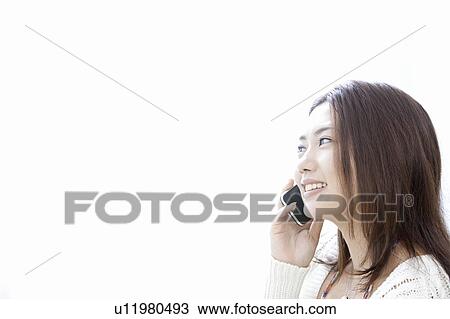 Stock Image - Young woman talking on smart phone, Tokyo Prefecture, Honshu, Japan. Fotosearch