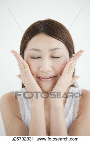 Stock Image - Young Woman Touching Her Face. Fotosearch