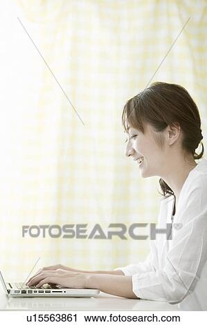 Stock Image - Young woman using a laptop, Tokyo Prefecture, Japan. Fotosearch