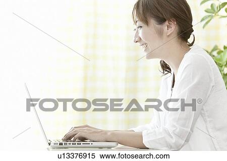 Stock Photography - Young woman using a laptop, Tokyo Prefecture, Japan. Fotosearch