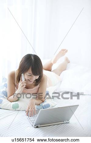 Picture - Young Woman Using Mobile Phone and Laptop. Fotosearch