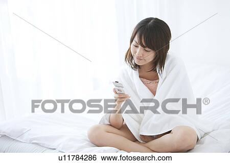 Stock Photograph - Young Woman Using Mobile Phone in Bed. Fotosearch