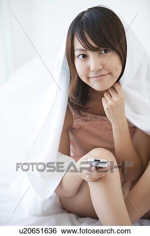 Stock Photograph - Young Woman Using Mobile Phone in Bed. Fotosearch
