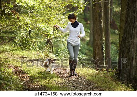 Stock Photo - Young Woman Walking Her Dog in Forest. Fotosearch