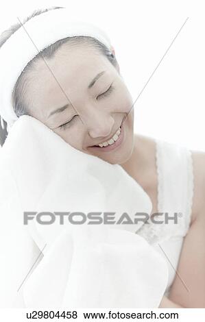 Stock Photo - Young woman wiping her face with a towel, Tokyo Prefecture, Japan. Fotosearch