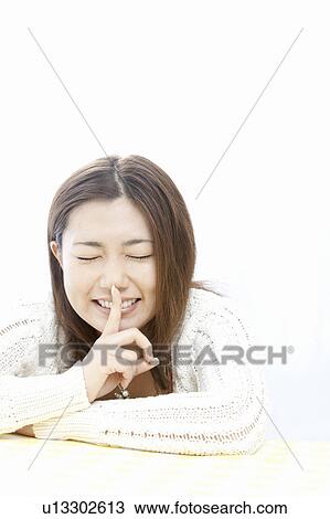 Stock Image - Young woman with finger on lips, Tokyo Prefecture, Honshu, Japan. Fotosearch