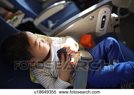 Boy sitting on an airplane holding a toy, Seoul, South Korea View Large Photo Image Stock Photography - Boy sitting on an airplane holding a toy, Seoul, South Korea. Fotosearch