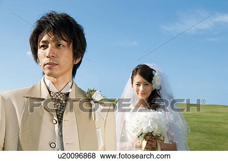 Bride and bridegroom standing and looking away View Large Photo Image Stock Photo - Bride and bridegroom standing and looking away. Fotosearch